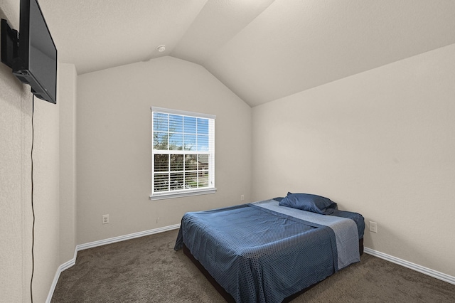 bedroom featuring lofted ceiling and dark colored carpet