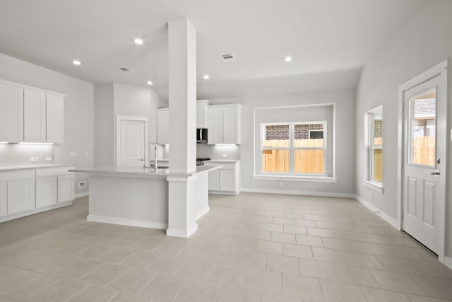 kitchen featuring light stone countertops, sink, a center island with sink, and white cabinets