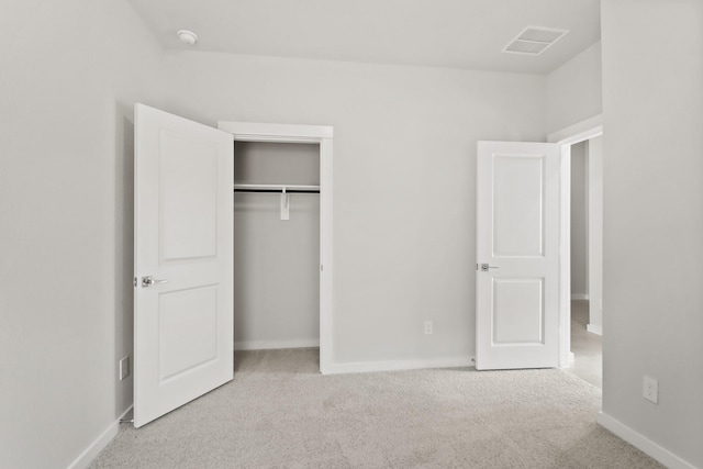 unfurnished bedroom featuring light colored carpet and a closet