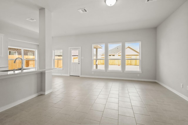 unfurnished living room featuring light tile patterned flooring and sink