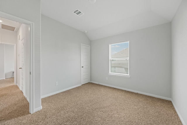 carpeted spare room featuring lofted ceiling