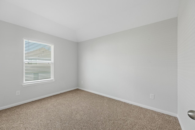 carpeted spare room featuring vaulted ceiling