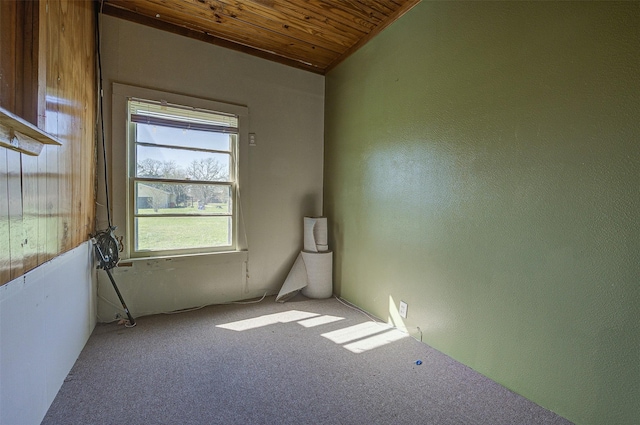 empty room with carpet floors, wood ceiling, and vaulted ceiling