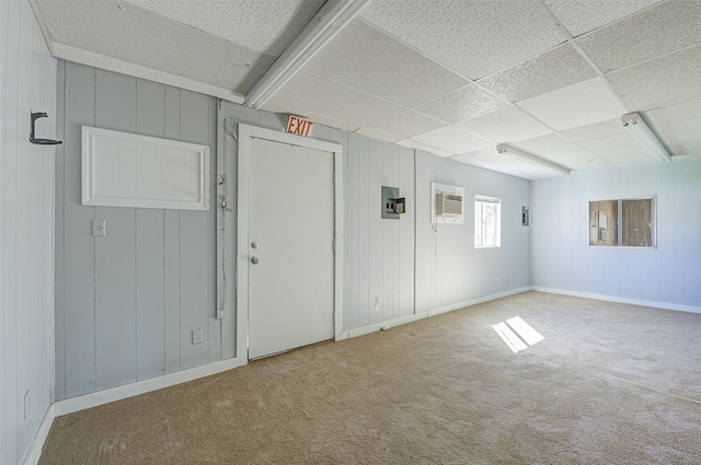 carpeted empty room with a paneled ceiling and a wall unit AC