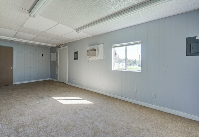 carpeted spare room featuring a paneled ceiling, electric panel, and a wall unit AC