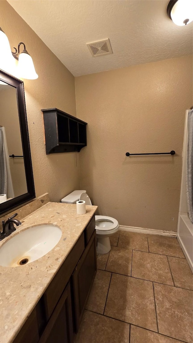 full bathroom with vanity, shower / bath combination with curtain, a textured ceiling, tile patterned floors, and toilet