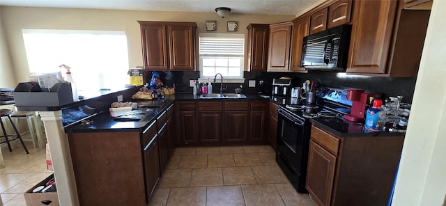 kitchen with sink, light tile patterned floors, black appliances, a kitchen bar, and kitchen peninsula