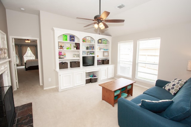 carpeted living room featuring a tiled fireplace and ceiling fan