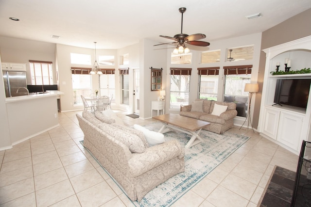 tiled living room featuring ceiling fan with notable chandelier