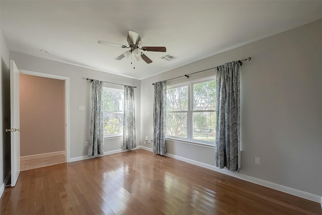 empty room with ceiling fan, wood-type flooring, and plenty of natural light