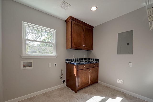 laundry area featuring light tile patterned flooring, cabinets, electric panel, hookup for a washing machine, and electric dryer hookup