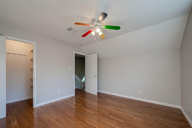 unfurnished bedroom with hardwood / wood-style flooring, ceiling fan, a spacious closet, and vaulted ceiling