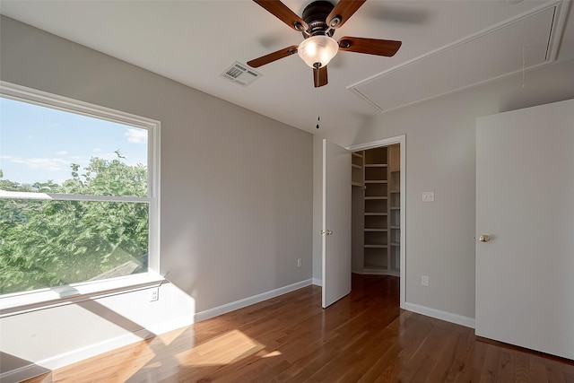 empty room with a wealth of natural light, dark hardwood / wood-style floors, and ceiling fan