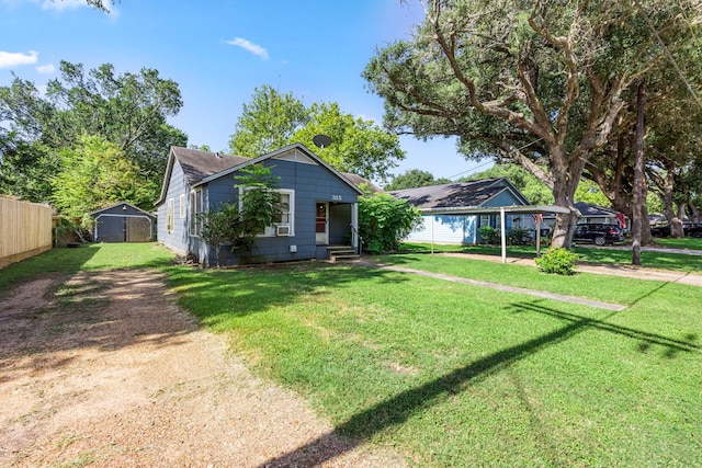 bungalow-style house featuring a carport, a storage unit, and a front yard