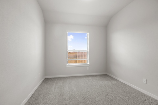 spare room featuring vaulted ceiling and carpet