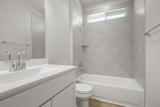 full bathroom featuring hardwood / wood-style flooring, tiled shower / bath, vanity, and toilet