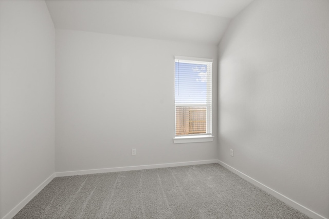 carpeted empty room with lofted ceiling