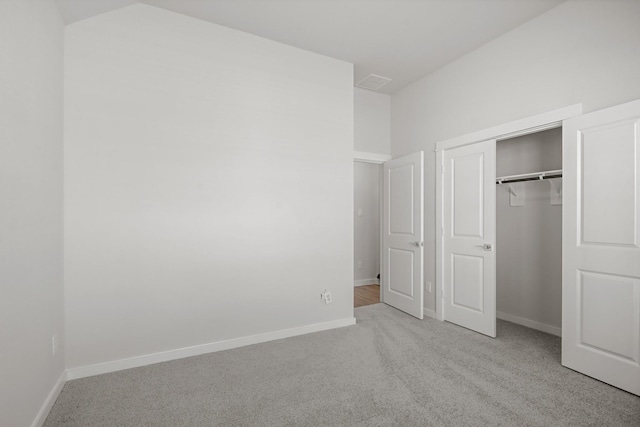 unfurnished bedroom with light carpet and a closet