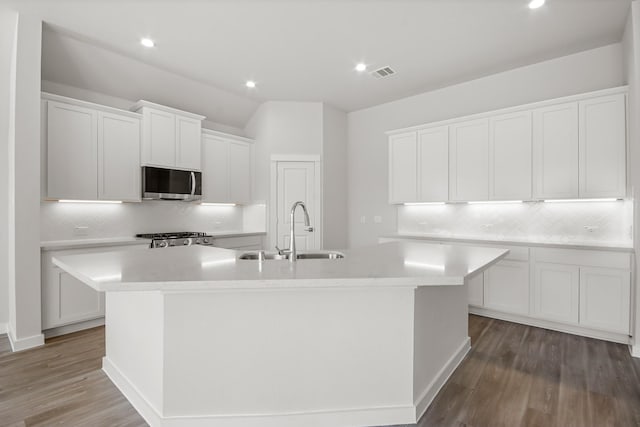 kitchen with sink, range, white cabinets, and a center island with sink