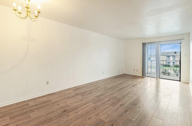 empty room with a notable chandelier and hardwood / wood-style flooring