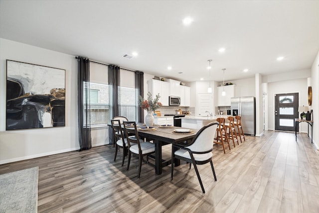 dining area with sink, light hardwood / wood-style floors, and a healthy amount of sunlight