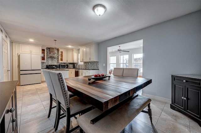 dining room with light tile patterned floors, ceiling fan, a textured ceiling, and baseboards