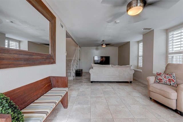 living area featuring stairs, light tile patterned floors, plenty of natural light, and visible vents