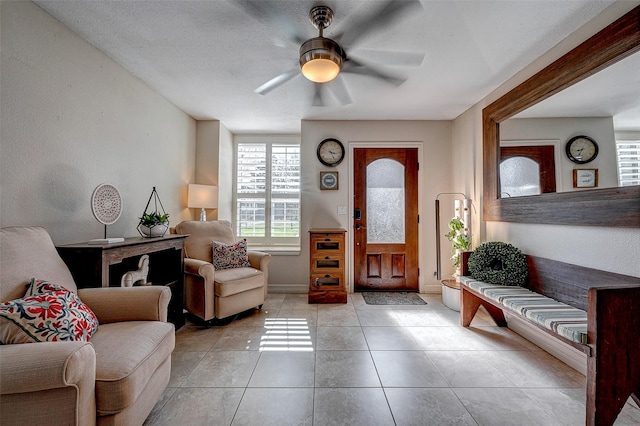 living area featuring ceiling fan, baseboards, and tile patterned floors