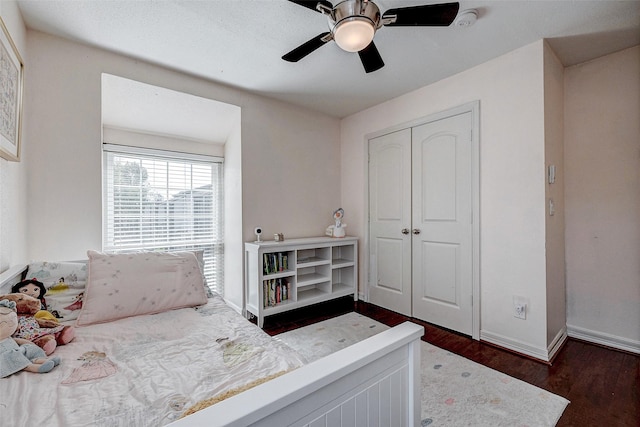 bedroom with ceiling fan, dark wood-type flooring, a closet, and baseboards