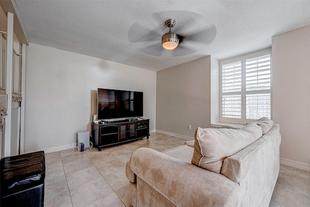 living area with ceiling fan, a textured ceiling, light tile patterned flooring, and baseboards