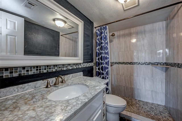 full bath featuring visible vents, toilet, a tile shower, a textured ceiling, and vanity