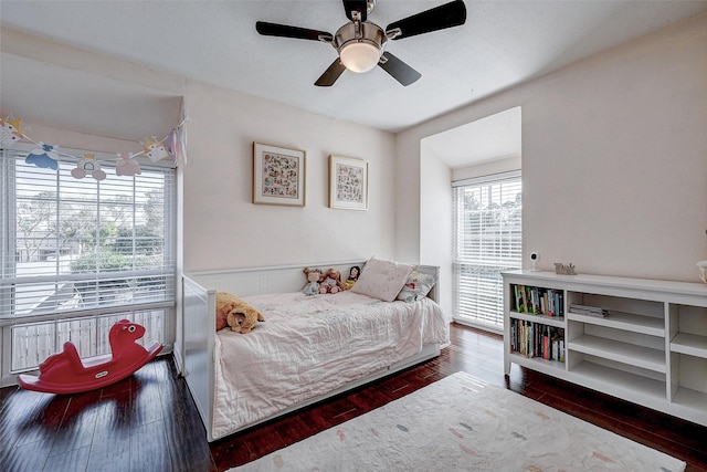 bedroom featuring a ceiling fan, wainscoting, and hardwood / wood-style floors