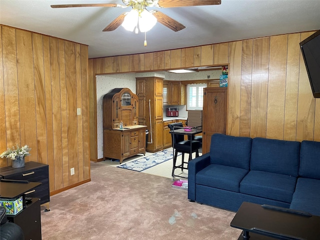 carpeted living room featuring ceiling fan and wood walls