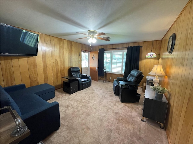 carpeted living room with wooden walls and ceiling fan