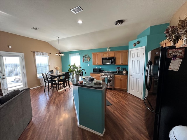 kitchen with dark hardwood / wood-style floors, pendant lighting, lofted ceiling, a kitchen island with sink, and black appliances