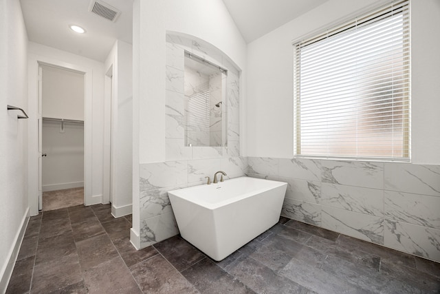 bathroom featuring tile walls and a tub