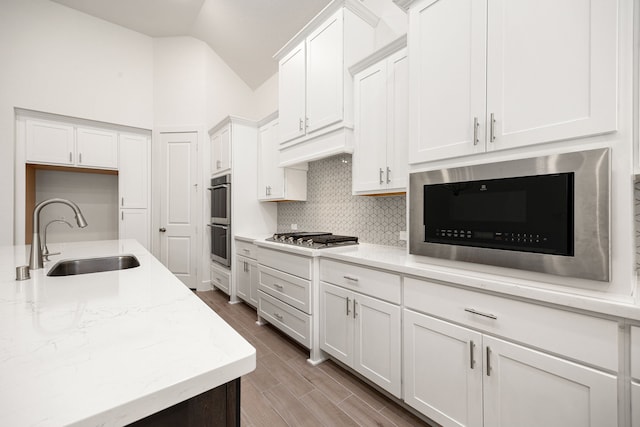 kitchen featuring white cabinetry, appliances with stainless steel finishes, sink, and lofted ceiling