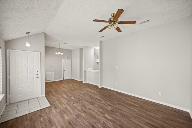 interior space featuring a textured ceiling, visible vents, vaulted ceiling, and wood finished floors