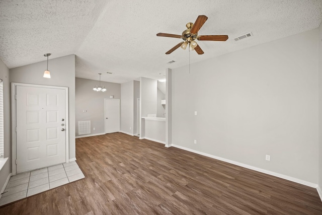 interior space with ceiling fan, a textured ceiling, wood finished floors, visible vents, and vaulted ceiling