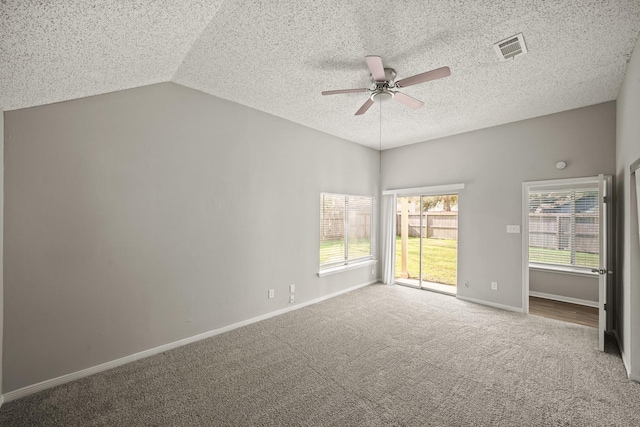 empty room with carpet floors, visible vents, baseboards, vaulted ceiling, and a ceiling fan