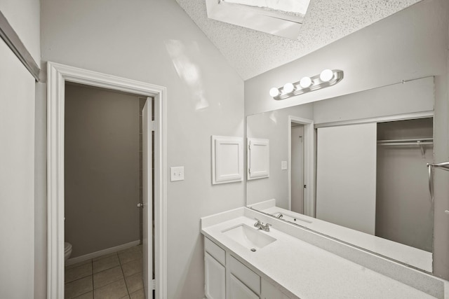 bathroom featuring a textured ceiling, tile patterned flooring, toilet, vanity, and baseboards