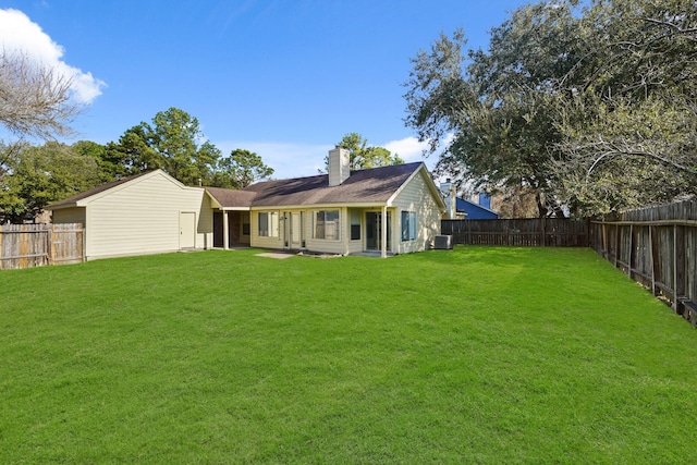 back of house with a yard, a chimney, and a fenced backyard