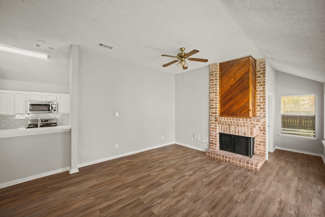 unfurnished living room with a fireplace, dark wood finished floors, lofted ceiling, visible vents, and baseboards