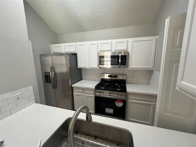 kitchen with appliances with stainless steel finishes, white cabinets, light countertops, and a sink