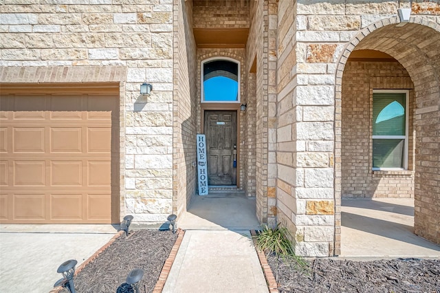 doorway to property with stone siding, brick siding, and an attached garage