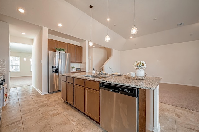 kitchen featuring pendant lighting, a center island with sink, stainless steel appliances, vaulted ceiling, and a sink