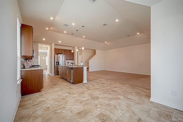 kitchen featuring visible vents, brown cabinetry, an island with sink, open floor plan, and stainless steel appliances