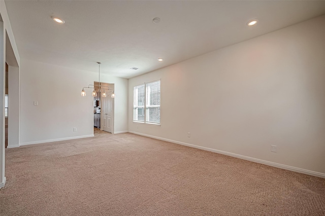 empty room with baseboards, recessed lighting, a notable chandelier, and light colored carpet