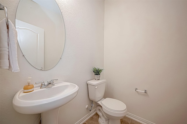 half bath with baseboards, a sink, and toilet