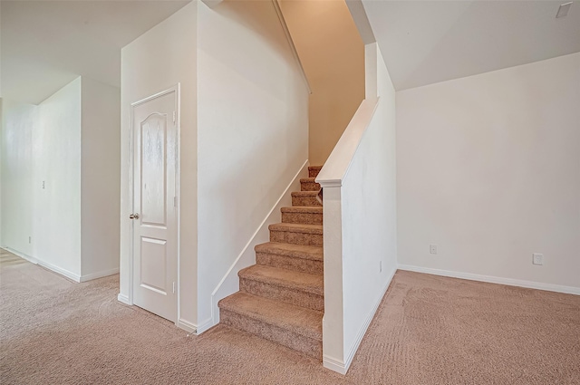 stairway featuring baseboards and carpet flooring